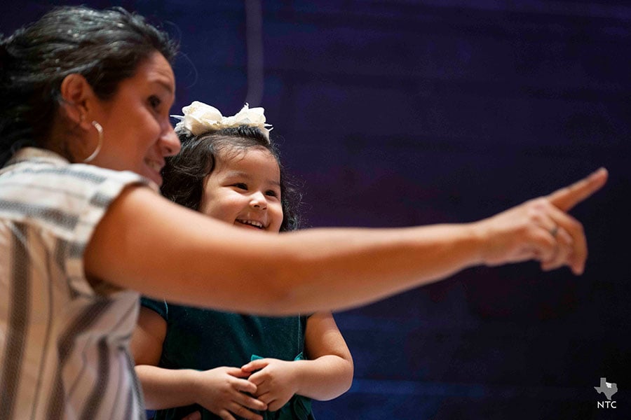 A woman points as a young girl looks over to the side